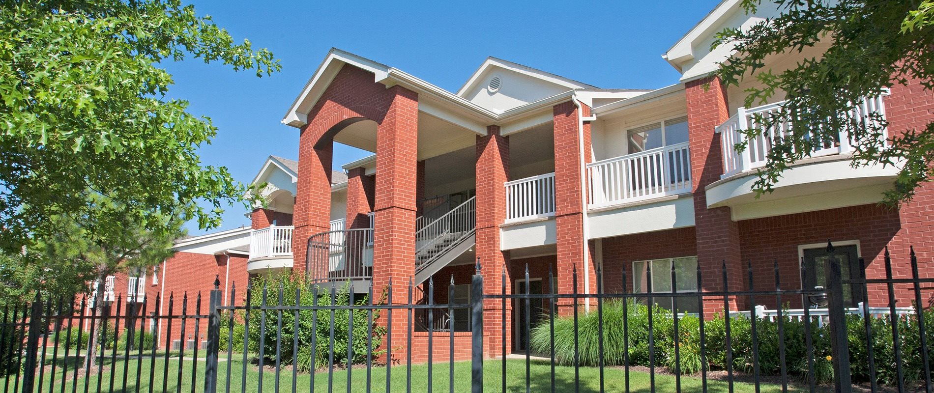 an apartment building with a black iron fence in front of it